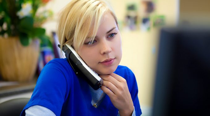 A seated female medical professional answering a cordless office phone